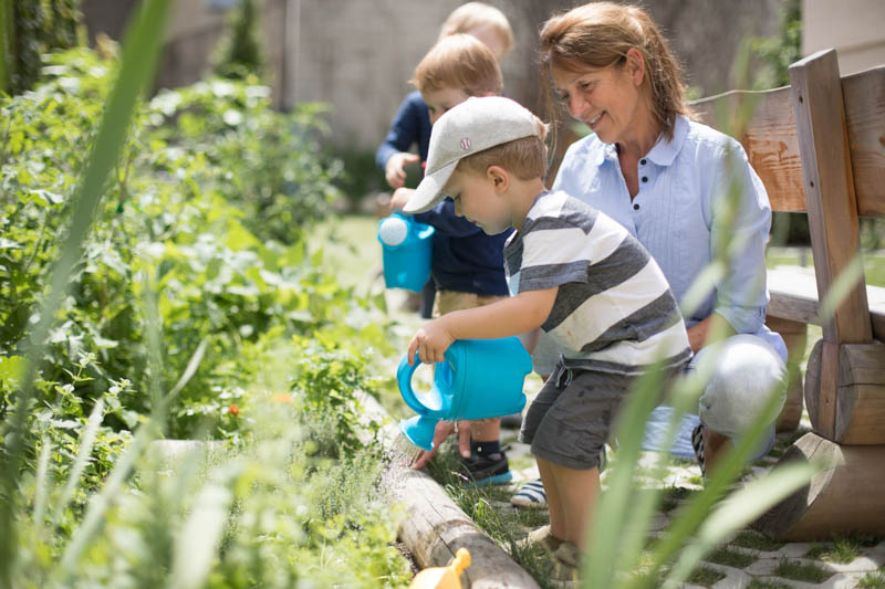 Kinder gießen Pflanzen im Garten