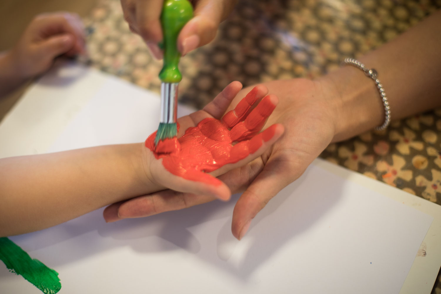 Kinderhandfläche wird mit roter Fingermalfarbe angepinselt