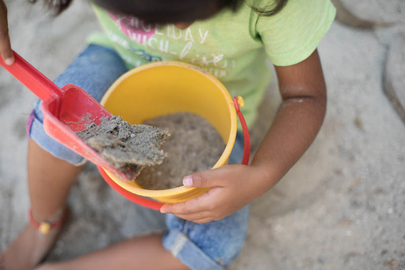 Kind rührt Sand in Eimer